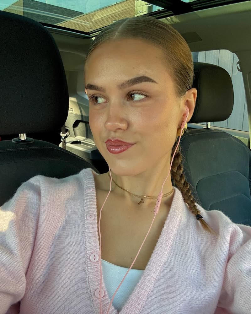 Selfie in de auto in een roze vest met roze oortjes met stipjes