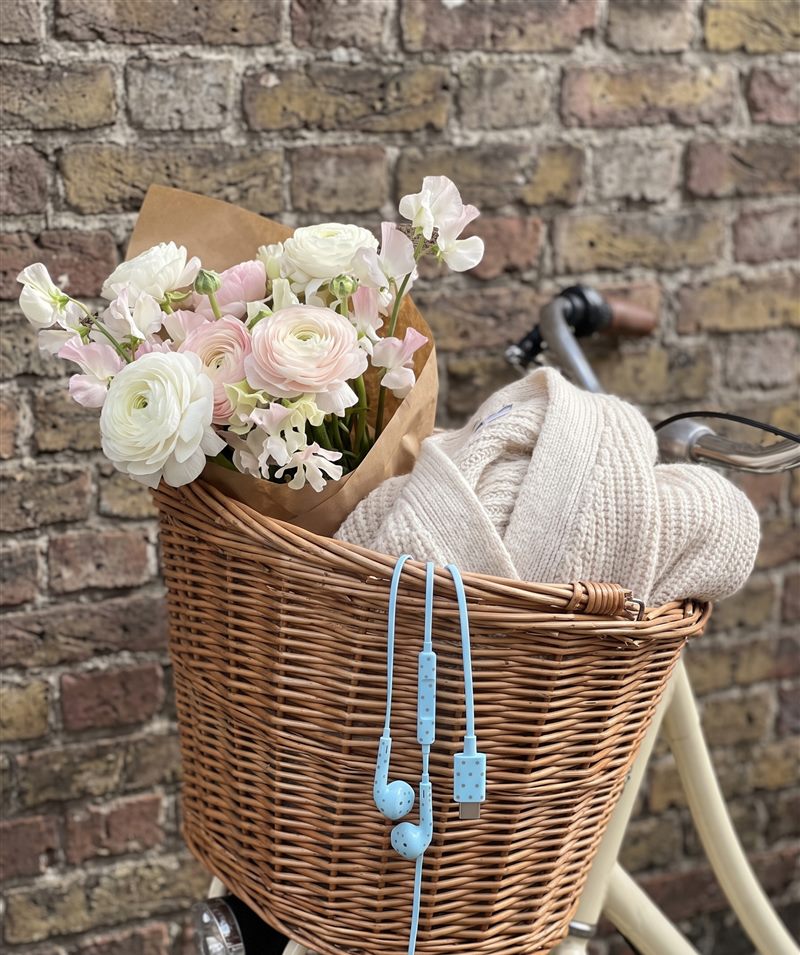 Babyblauwe oortjes aan een fietsmand met bloemen en een vest