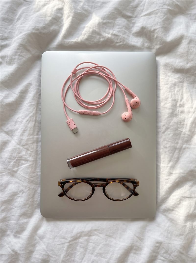 Roze oortjes op een laptop met lipgloss en een schildpad bril