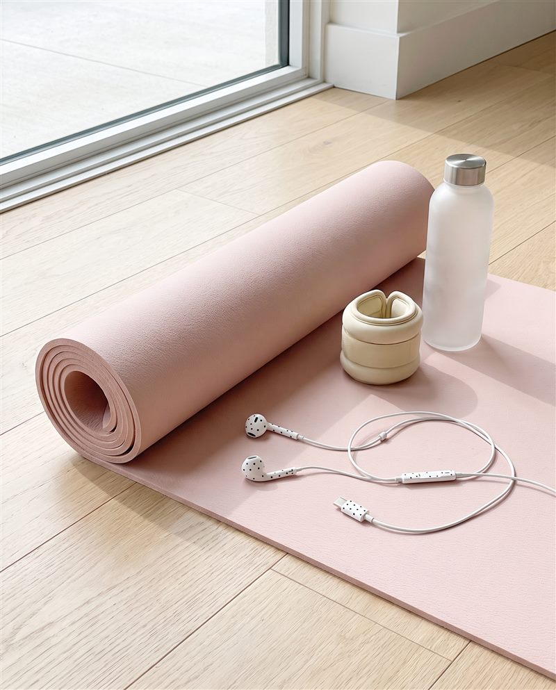 Witte oortjes op een roze pilatesmat met enkelgewichten