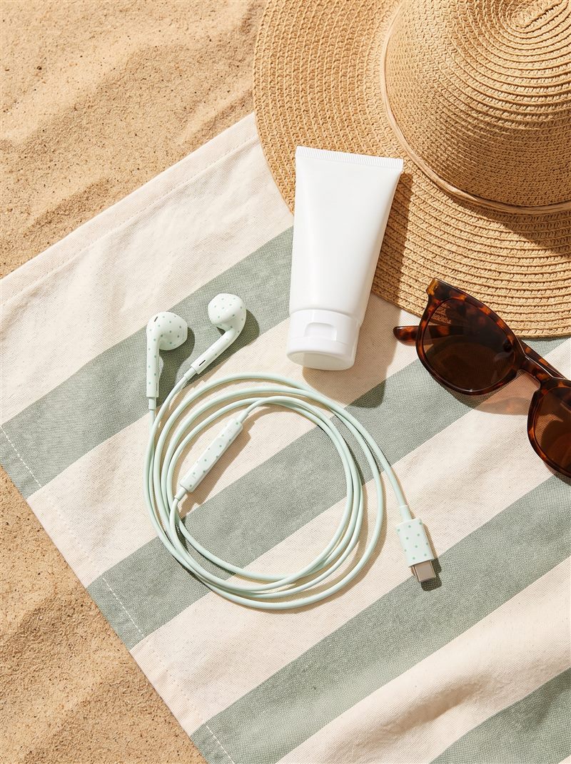 Mint oortjes op een gestreepte strandhanddoek met strohoed en zonnebril