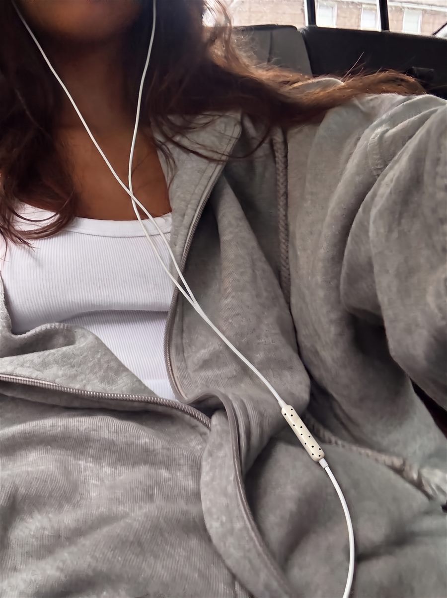 Selfie in de auto met grijze hoodie en witte oortjes met zwarte stipjes